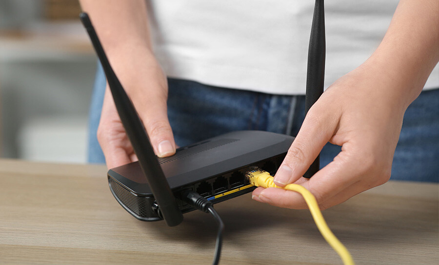 An image showing an ethernet cable being plugged into a router to set up a wireless LAN .